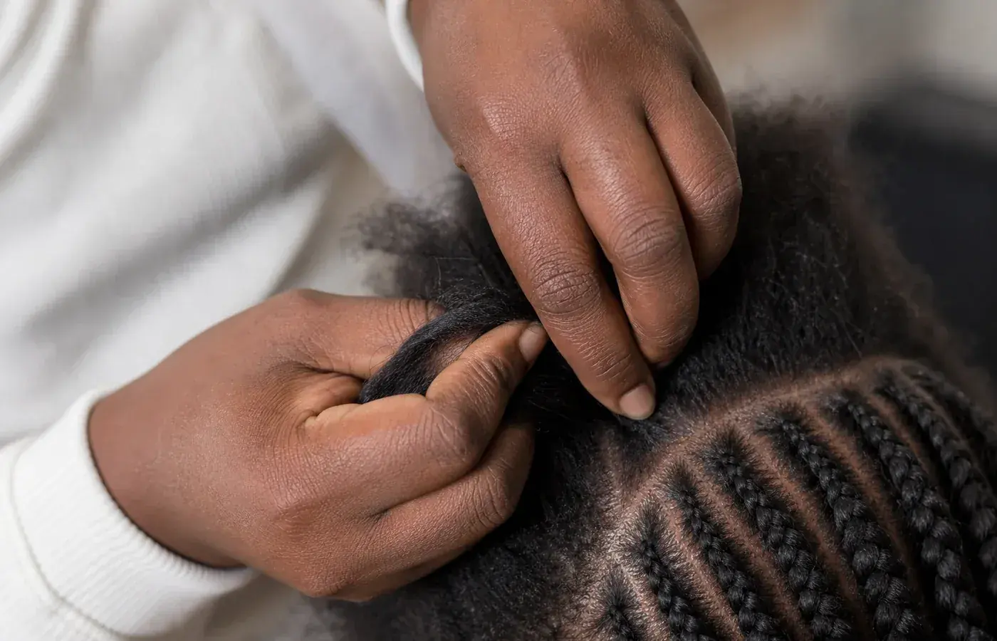 Mãos a preparar com precisão a base de um penteado entrançado